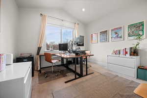 Home office with light colored carpet and lofted ceiling