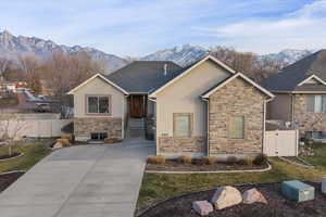 View of front facade with stucco siding, a mountain view, a gate, and driveway