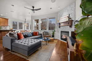 Living area with a stone fireplace, wood finished floors, a ceiling fan, and recessed lighting