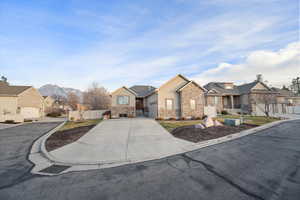 View of front of house with a residential view, driveway, stucco siding, and stone siding