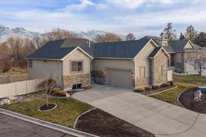 View of front of house featuring stucco siding, stone siding, concrete driveway, and a mountain view