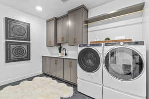 Laundry room with dark tile patterned floors, cabinet space, washer and dryer, and recessed lighting