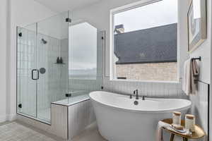 Bathroom with a freestanding tub, a shower stall, and tile patterned flooring