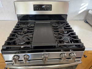 Kitchen view of gas stove, a textured wall, and light countertops