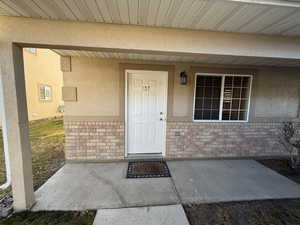 Entrance to property featuring a porch, brick siding, and stucco siding