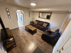 Living area with arched walkways and hardwood / wood-style floors