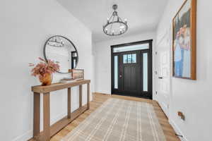 Foyer with light wood finished floors and a chandelier