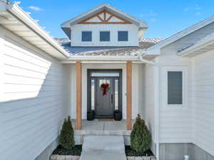 View of exterior entry featuring roof with shingles