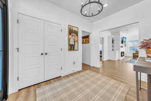 Entryway with a lit fireplace, a chandelier, and light wood-type flooring
