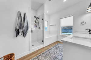 Full bathroom with a stall shower, double vanity, light wood-type flooring, and a garden tub