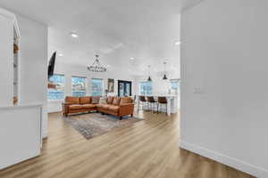 Living room featuring a chandelier, light wood-style flooring, and recessed lighting
