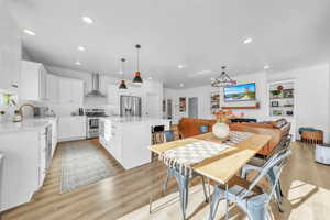 Dining area with light wood finished floors, a chandelier, recessed lighting, and built in features