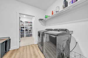 Washroom with light wood-style flooring and independent washer and dryer