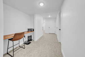 Home office featuring light carpet and built in study area