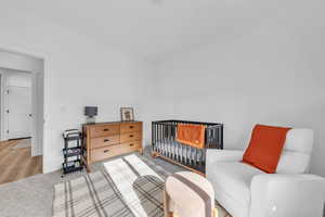 Carpeted bedroom with baseboards and a crib