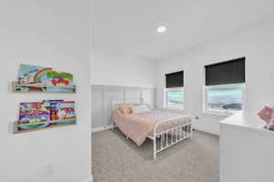 Bedroom featuring a decorative wall, wainscoting, and light carpet
