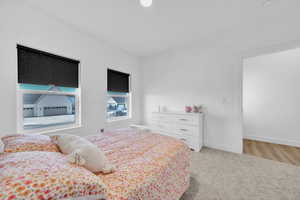 Bedroom with light colored carpet and baseboards