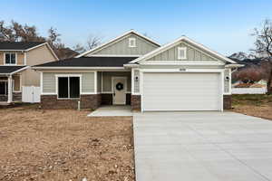 Craftsman-style home featuring board and batten siding, a garage, concrete driveway, and stone siding