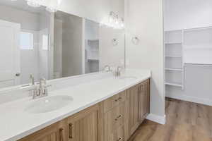 Bathroom with a walk in closet, double vanity, and light wood-style flooring