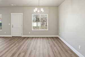 Unfurnished dining area with light wood-style flooring and a chandelier