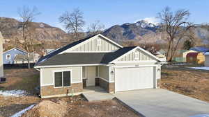 Craftsman house featuring board and batten siding, roof with shingles, concrete driveway, an attached garage, and stone siding