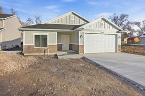 View of front of property with board and batten siding, concrete driveway, a shingled roof, an attached garage, and stone siding