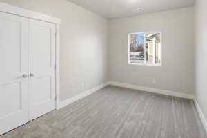 Unfurnished bedroom with light carpet and a closet