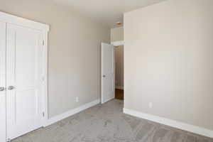 Unfurnished bedroom with carpet flooring and baseboards
