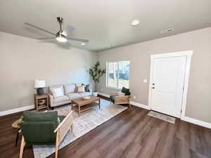 Living area featuring dark wood-type flooring, a ceiling fan, and recessed lighting