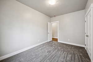 Unfurnished bedroom with dark carpet and a textured ceiling