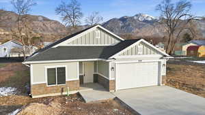 View of front of property featuring board and batten siding, a shingled roof, driveway, and stone siding