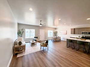 Living room with light wood finished floors, suspended lighting, a textured ceiling, and a ceiling fan
