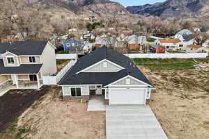 View of front of home with board and batten siding, concrete driveway, an attached garage, a mountain view, and a residential view