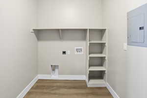 Washroom featuring electric panel, light wood-style floors, electric dryer hookup, and hookup for a washing machine