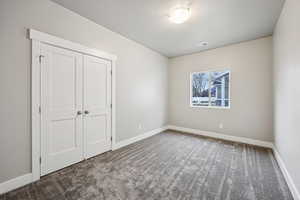 Unfurnished bedroom with light carpet and a closet