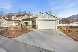 Craftsman-style house with a mountain view, covered porch, board and batten siding, driveway, and an attached garage