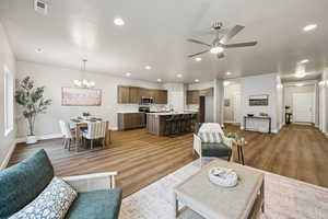 Living area featuring a chandelier, ceiling fan, and dark wood-style flooring