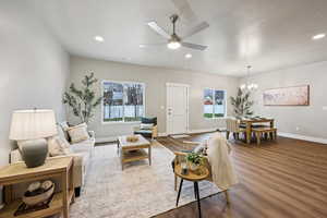 Living room with ceiling fan, dark wood finished floors, and a chandelier