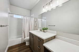 Full bath featuring vanity, shower / bath combo, and dark wood-style floors