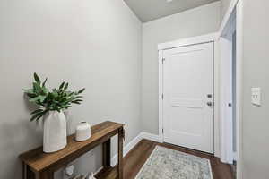 Doorway with wood finished floors and baseboards