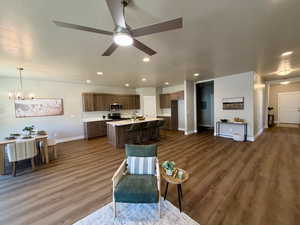 Living area with suspended lighting, dark wood finished floors, and a ceiling fan