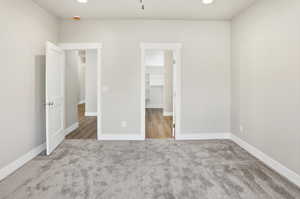 Unfurnished bedroom with a spacious closet, light carpet, and recessed lighting