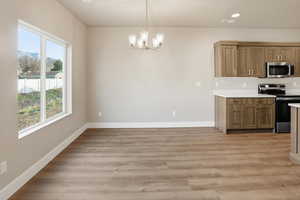 Kitchen featuring stainless steel appliances, light countertops, decorative light fixtures, light wood-style flooring, and recessed lighting