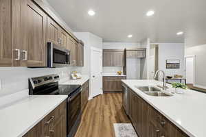 Kitchen featuring stainless steel appliances, dark wood-type flooring, light stone countertops, and recessed lighting