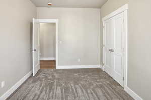 Unfurnished bedroom featuring dark colored carpet and a closet
