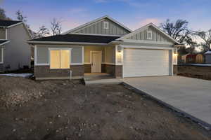 View of front of property with board and batten siding, driveway, and a garage