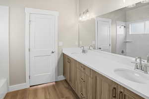 Bathroom featuring double vanity, dark wood finished floors, and shower / washtub combination