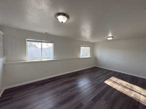 Spare room featuring a textured ceiling and dark wood finished floors