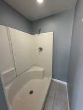 Full bath featuring a shower and light tile patterned floors