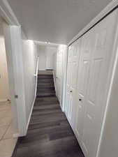 Corridor with a textured ceiling, dark wood-style floors, and stairs